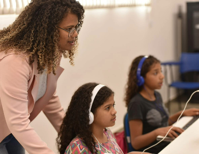 Professora e duas alunas em uma sala de informática