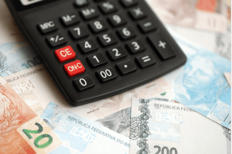 Calculadora sobre várias notas de reais, representando o conceito de organização e controle financeiro no Brasil.