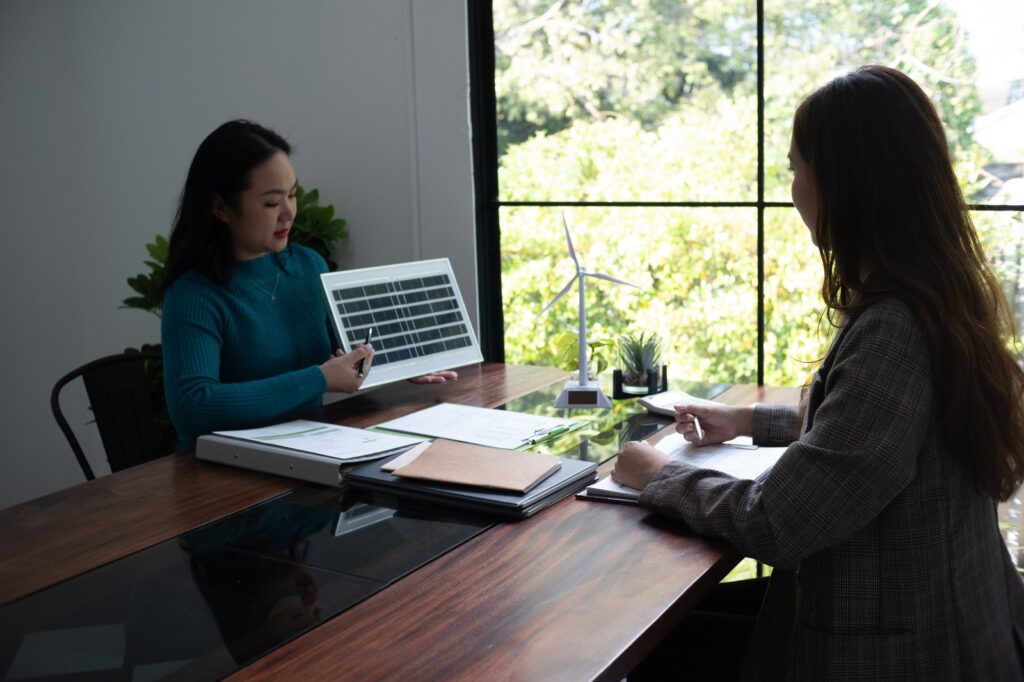 Consultora apresentando análise de eficiência energética e painel solar fotovoltaico para cliente em reunião sobre soluções de energia limpa e renovável